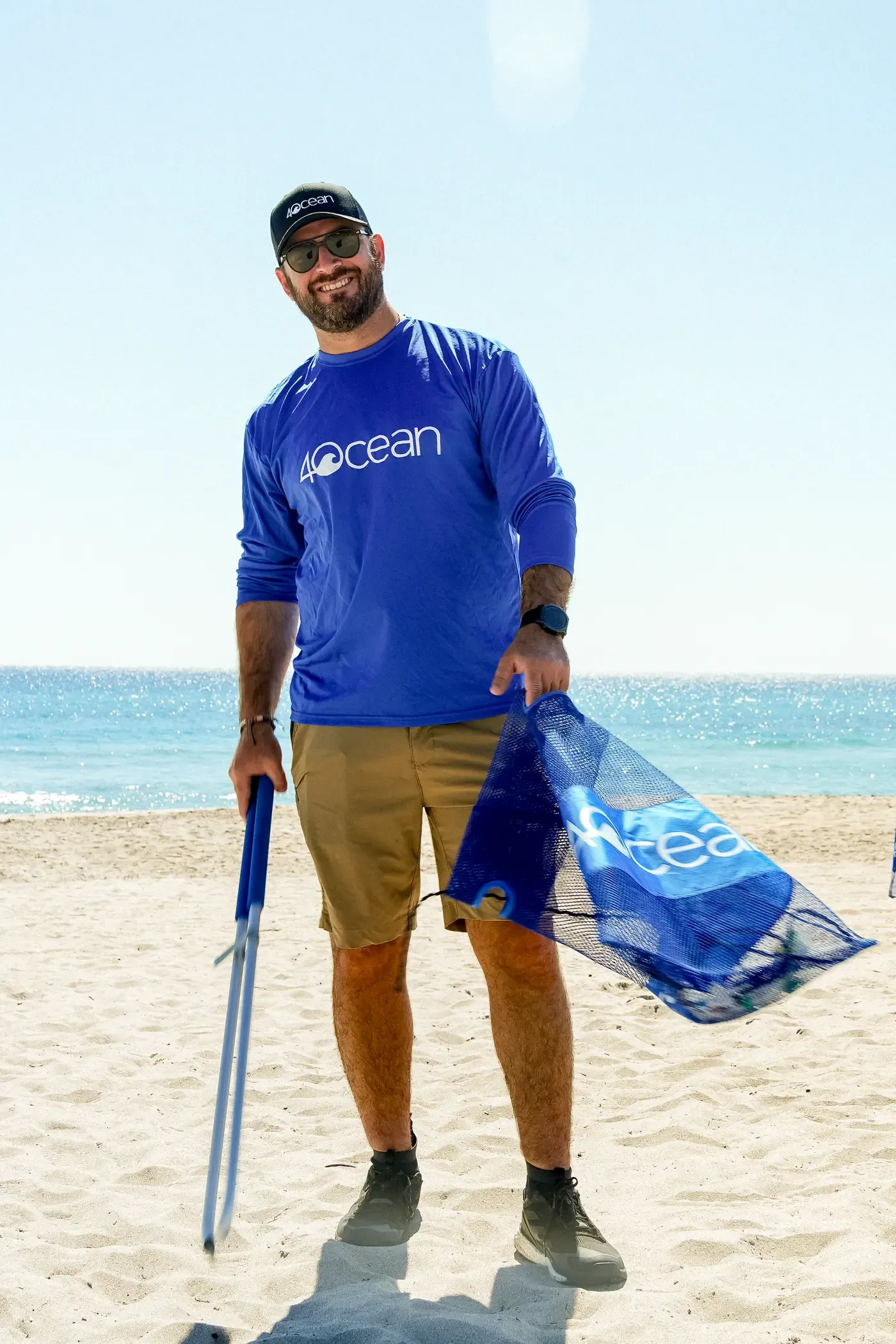 A 4ocean crew member carrying a collection bag along the shoreline