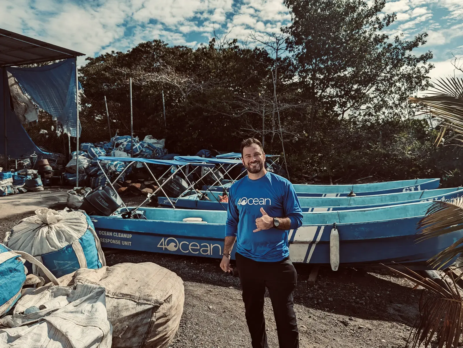 Grant beside a 4ocean boat loaded with bags of recovered plastic