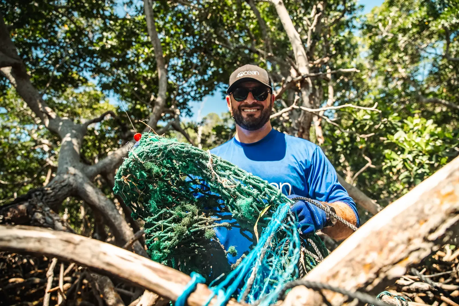 Grant carrying a recovered fishing net out of a mangrove