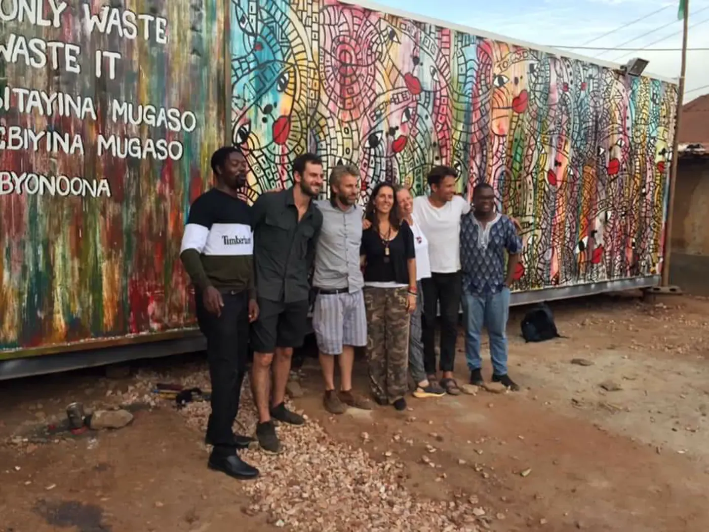 Grant with local partners in front of a painted mural in Uganda